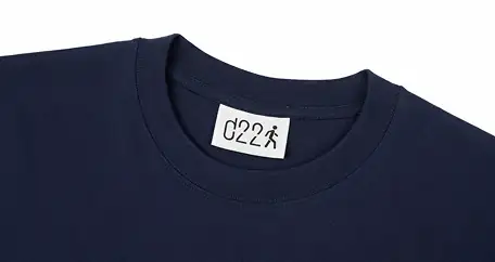 Close-up of a navy blue t-shirt with a white detour22 woven label sewn onto the inside neck.